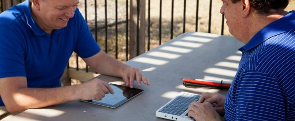 un aveugle utilisant son Braille Sense U2 Azerty en face d'un collègue avec une tablette