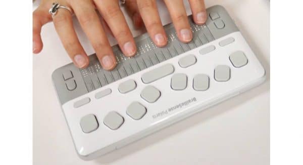 Doigts posés sur le Bloc note Braille Sense polaris mini