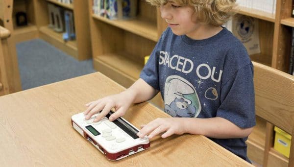 un jeune étudiant avec le Bloc note Braille Sense U2 Perkins