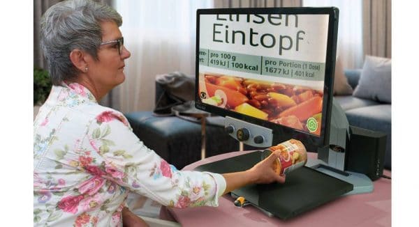 une femme lit une boite de conserve avec le téléagrandisseur parlant VEOVOX