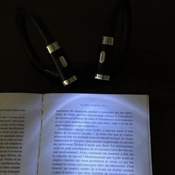lampe tour de cou éclairant un livre posé sur une table